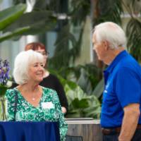 Deb Barko standing by table at event, chatting with male coworker